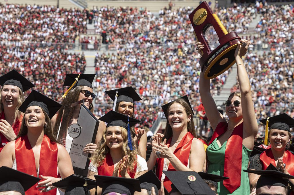 Members of the UW Women's Volleyball team smile and hold up their NCAA Championship trophies at the 2025 Commencement Ceremony