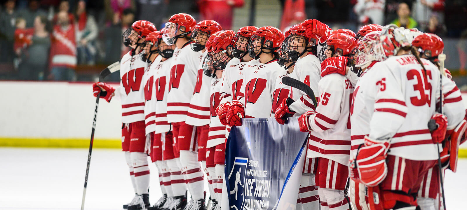 A winning women's hockey team lines up on the ice at the Kohl Center to accept their NCAA championship win.
